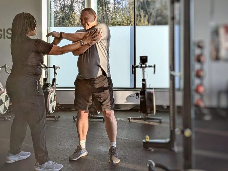 "Sophia assisting a male client with an arm stretch in the gym."