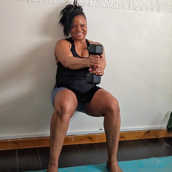 "Sophia demonstrating a forward facing lunge stretch at home on a pink mat with leg against red sofa."